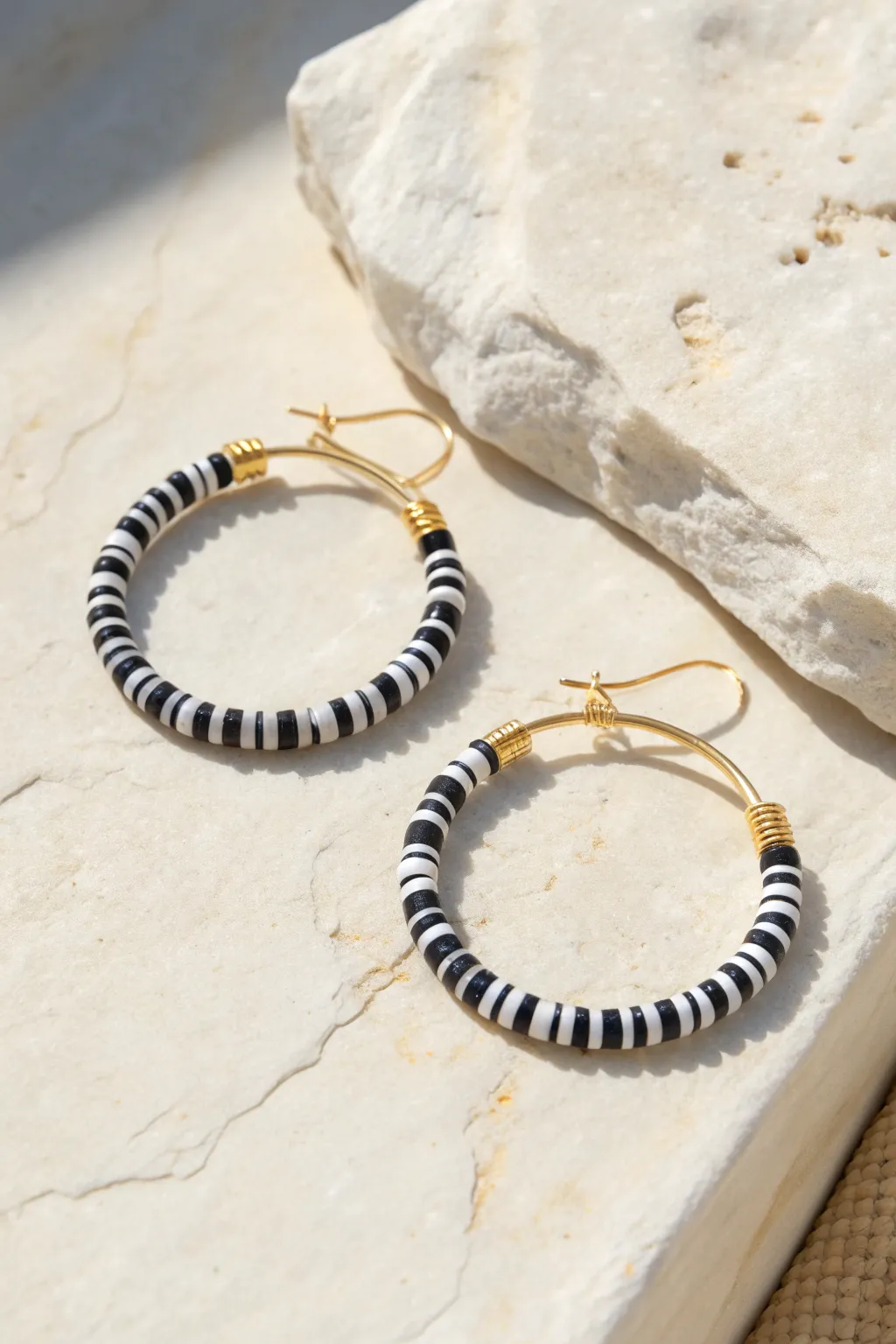 High-contrast black and white heishi hoop earrings on stone, minimalist and boho clay inspo