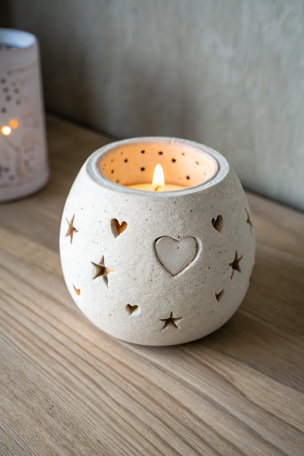 Simple clay tea light holder with star and heart cutouts, glowing warmly in a cozy vibe