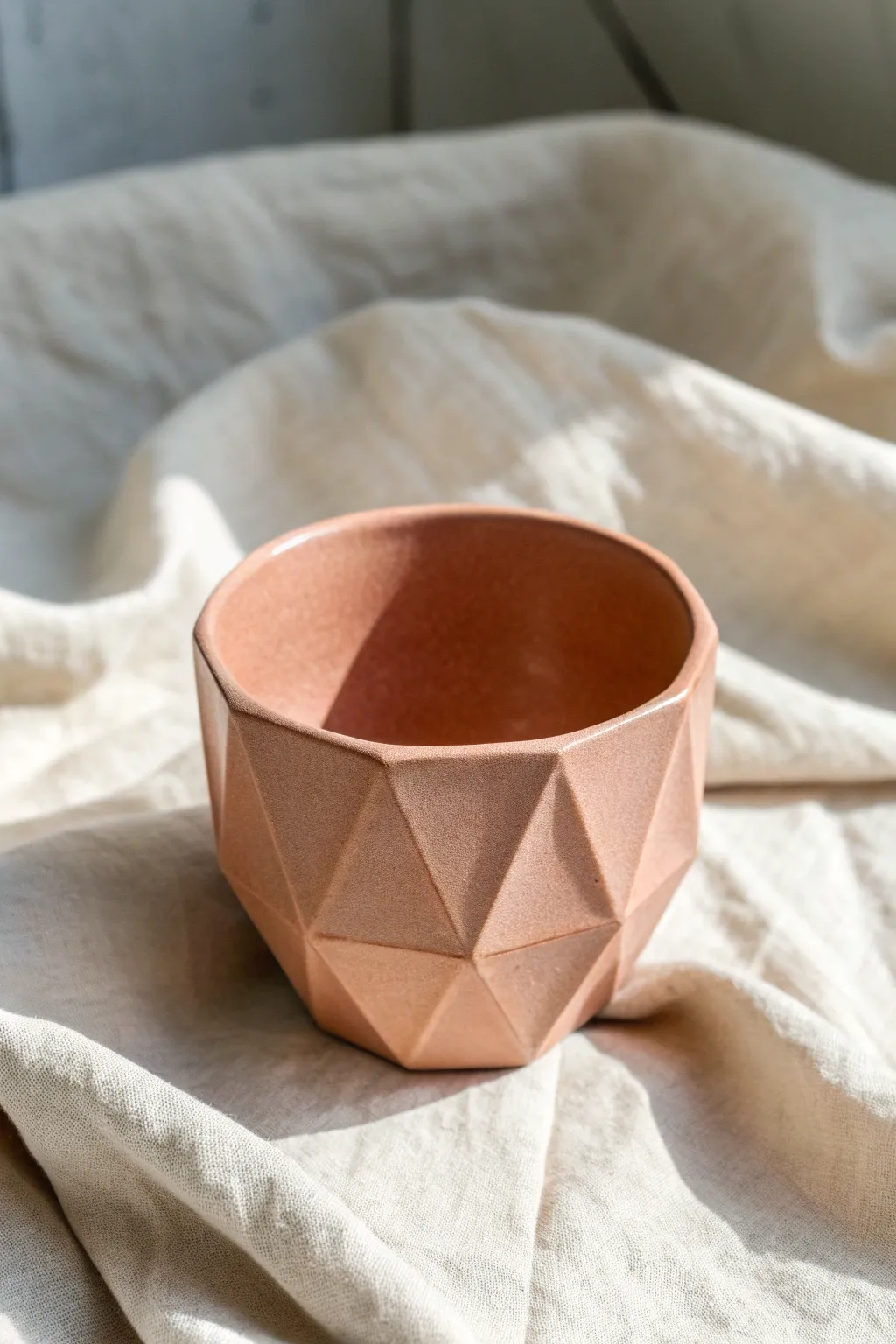 Faceted clay cup in a soft matte glaze, crisp planes catching light for minimalist charm.