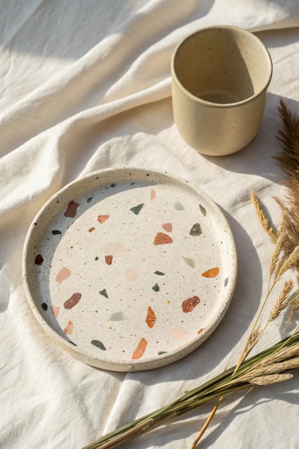 Terrazzo chip clay plate in soft pastels, minimalist overhead styling with warm natural light