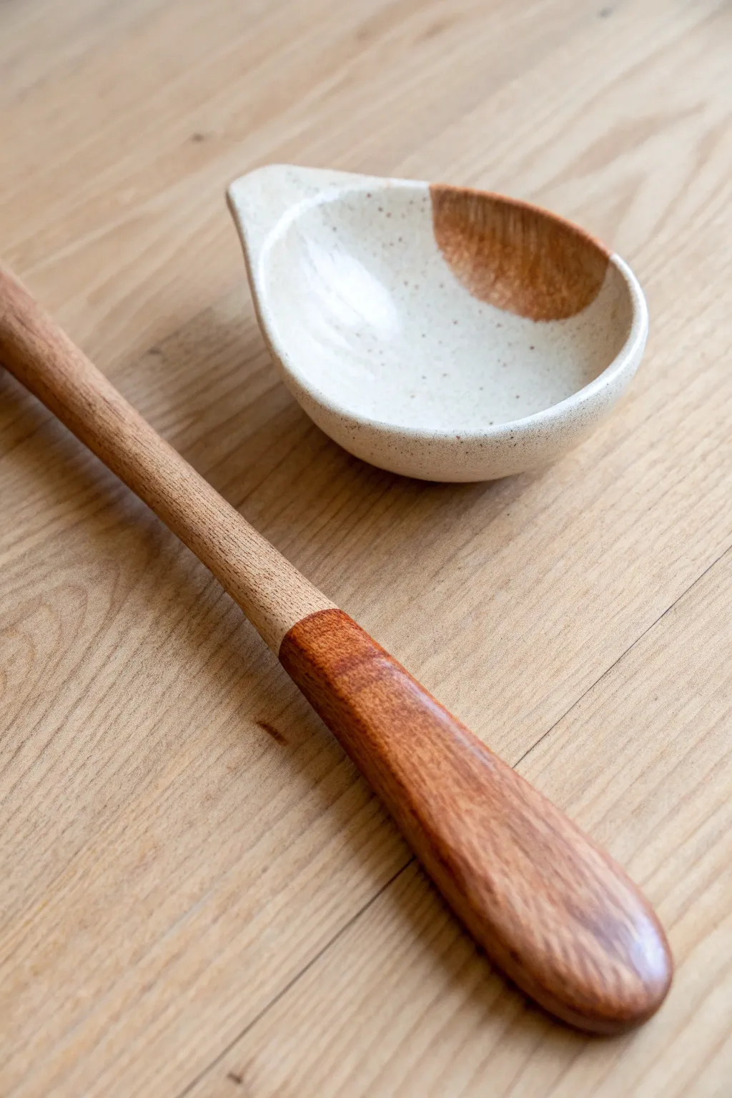 Two-tone dip-glazed clay spoon on pale wood, minimalist Scandinavian style with soft boho warmth