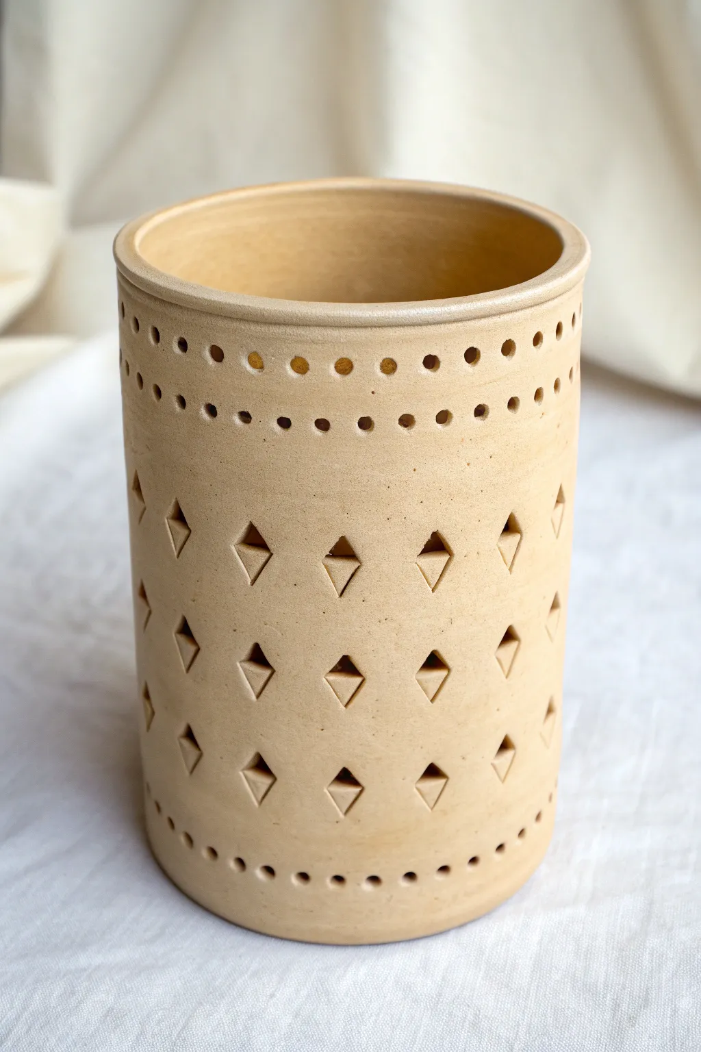 Lantern-style clay holder with pierced dot grids for airy light and tactile texture.