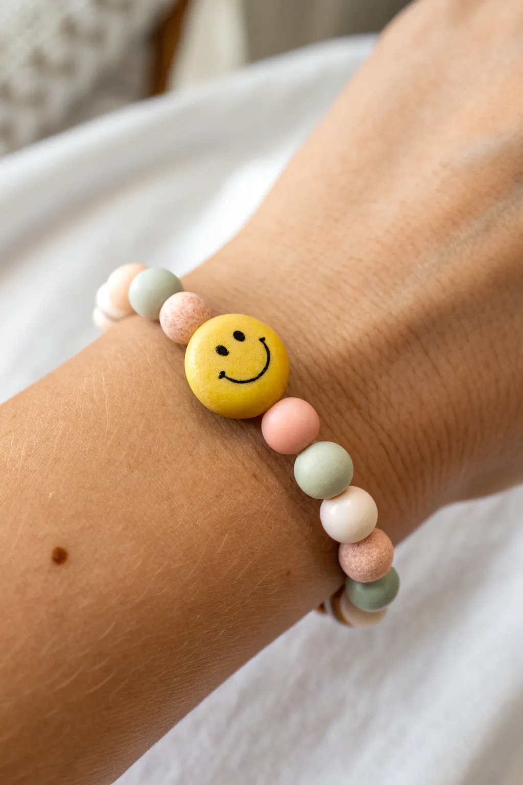 A cheerful single-smiley focal bead bracelet with soft pastel clay beads and cozy boho vibes.
