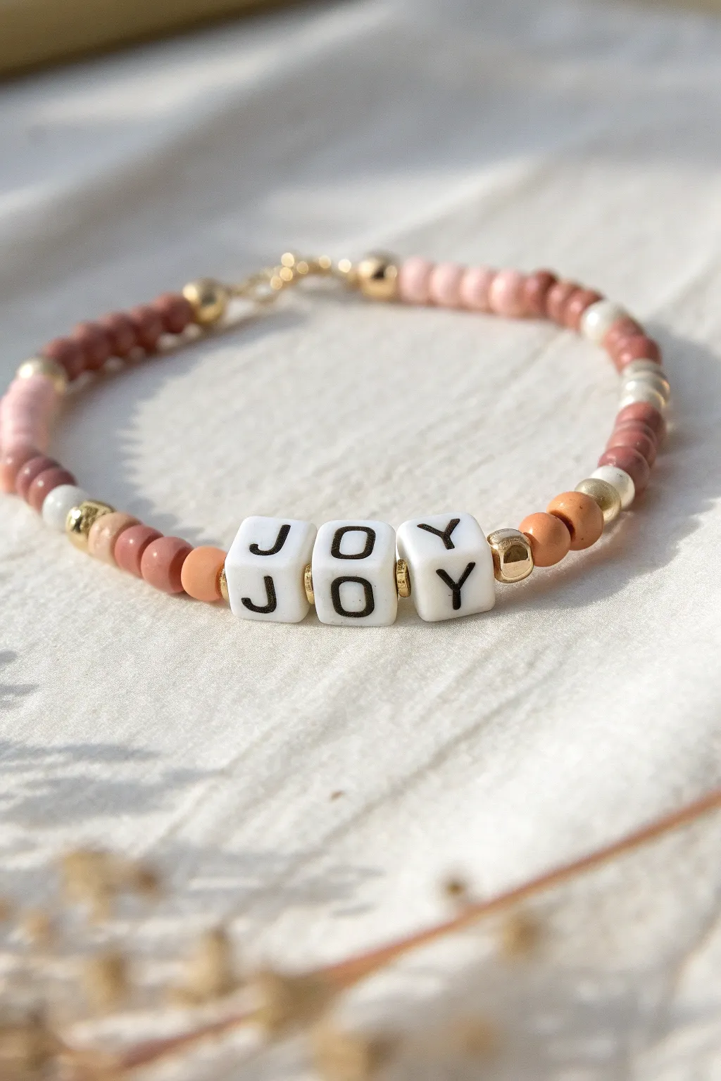 Minimal clay bead bracelet with JOY letter beads and pastel heishi accents for sunny vibes.