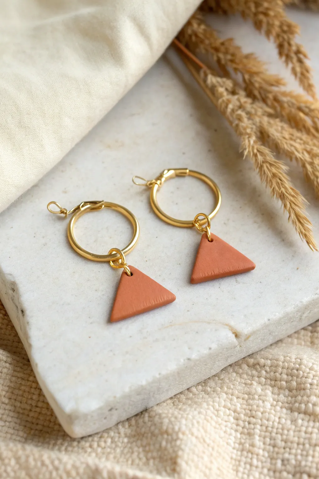 Minimal clay charm hoops in warm terracotta on gold hoops, an easy cut-and-bake earring idea.