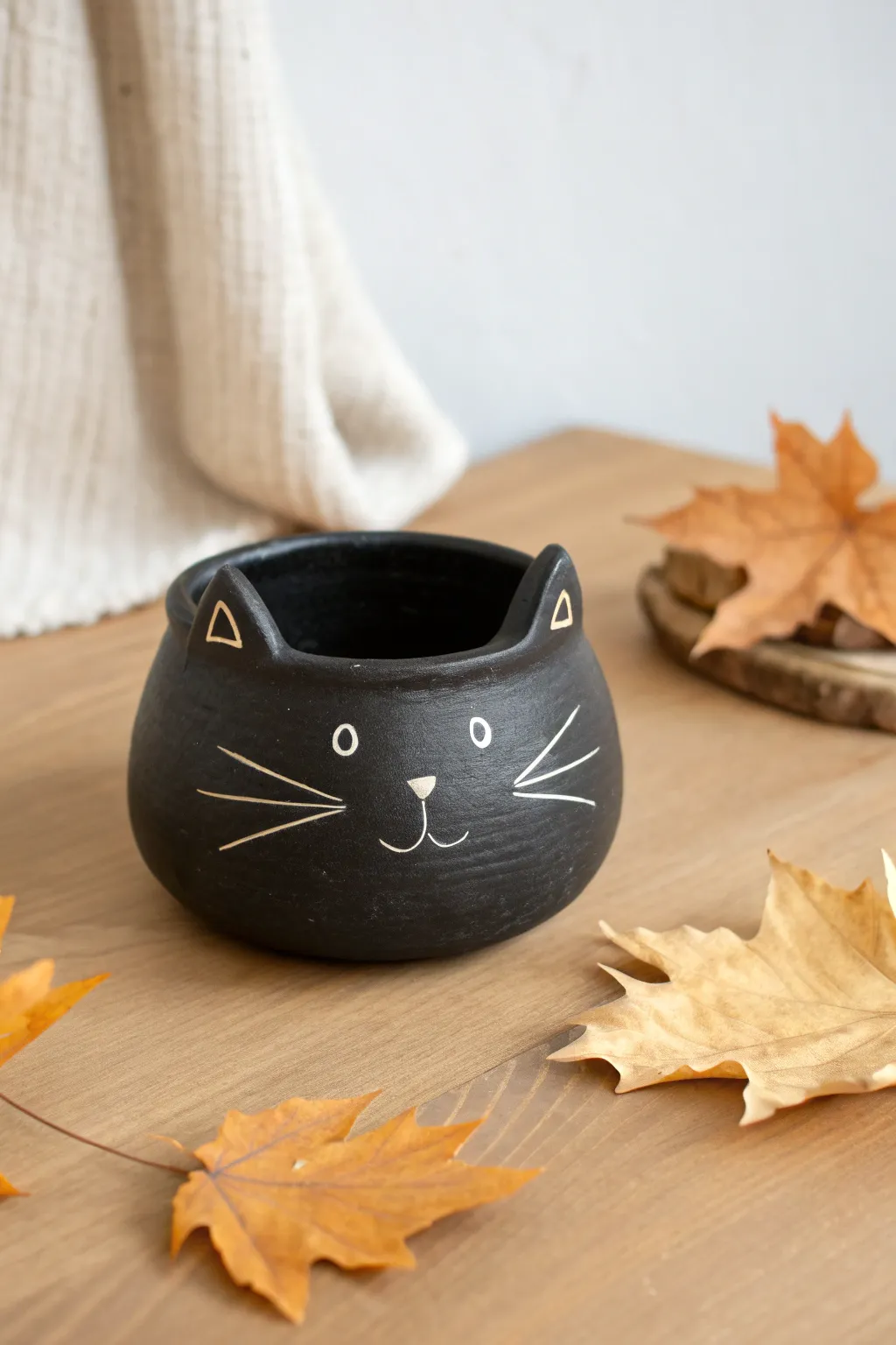 Minimal black cat pinch pot with pointy ears and bright eyes, perfect for cozy Halloween decor.