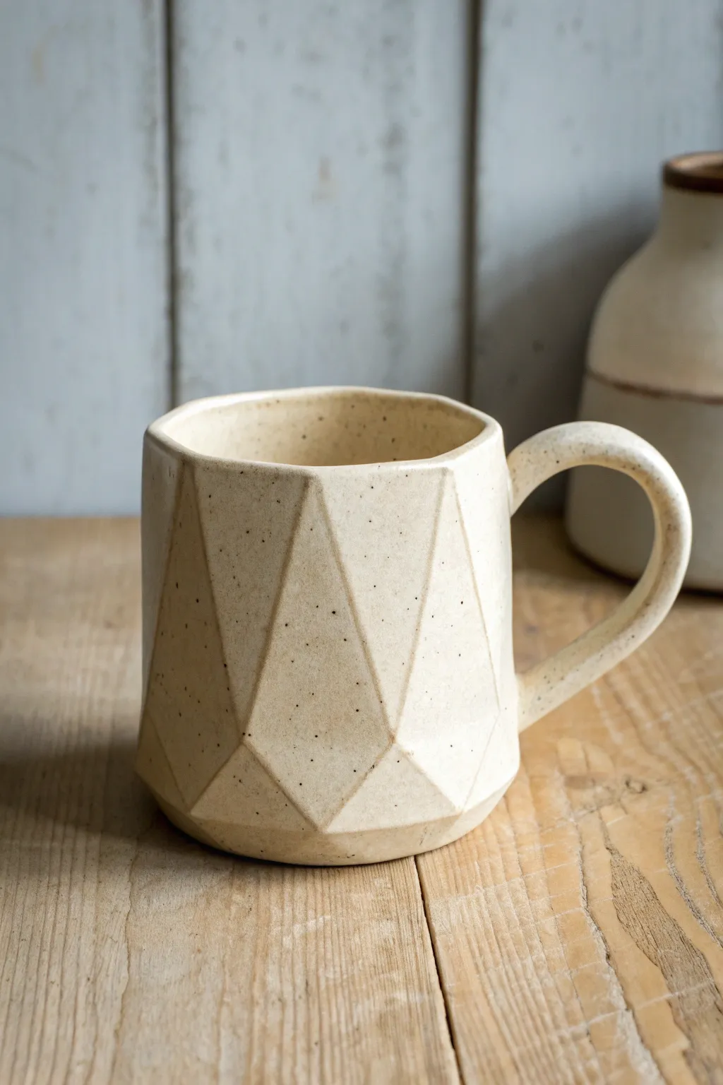 Faceted slab-built mug in satin ivory glaze, modern geometry with soft handmade warmth.