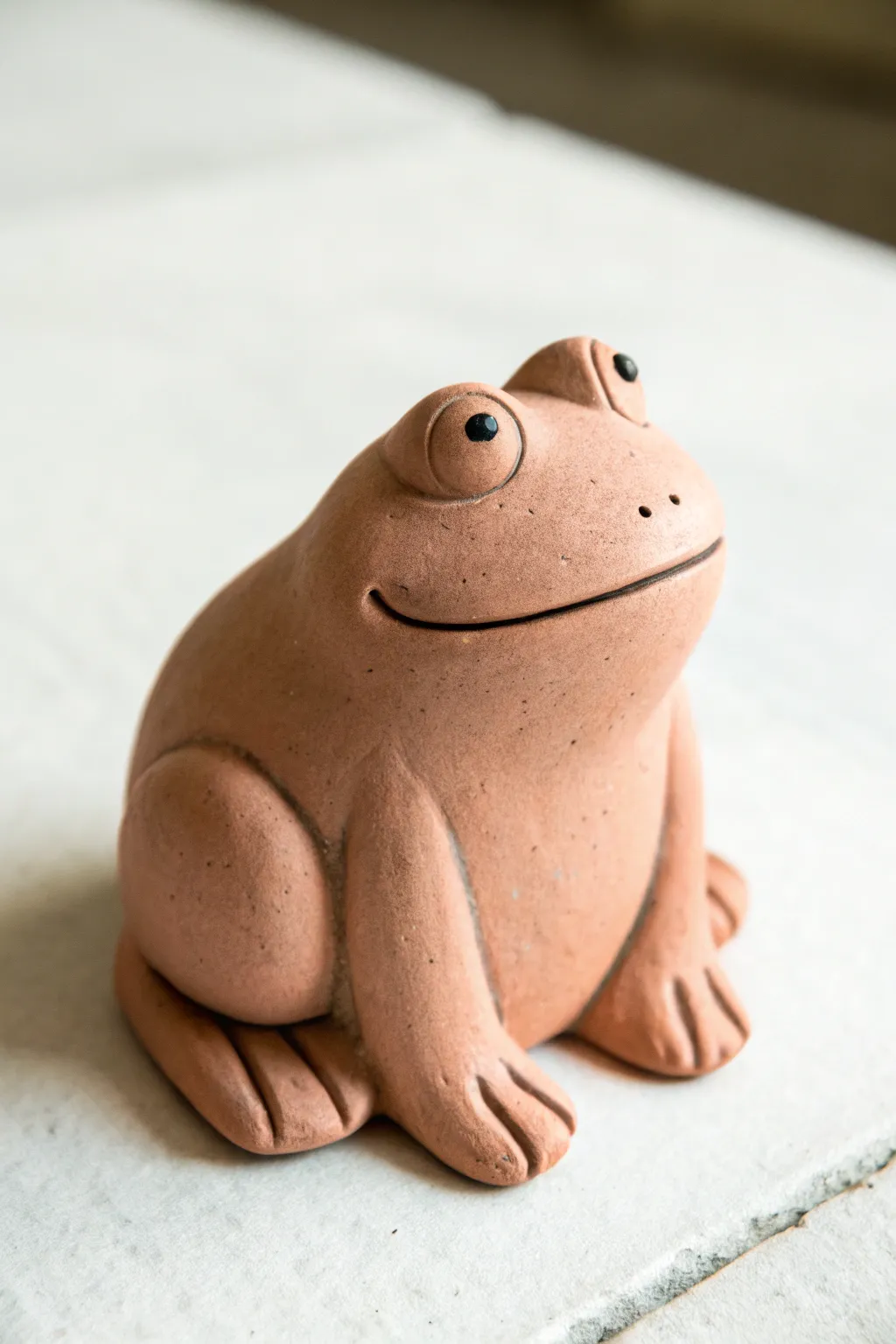 A simple one-color clay frog with a carved smile and pressed toes for sweet minimalist charm.