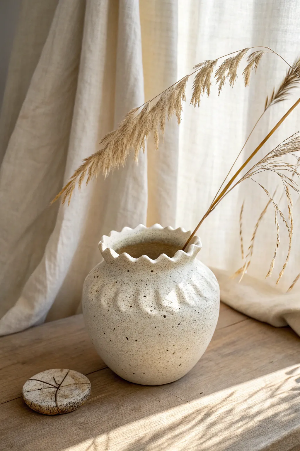Scalloped rim pinch pot vase with a single stem, minimal styling and soft natural contrast