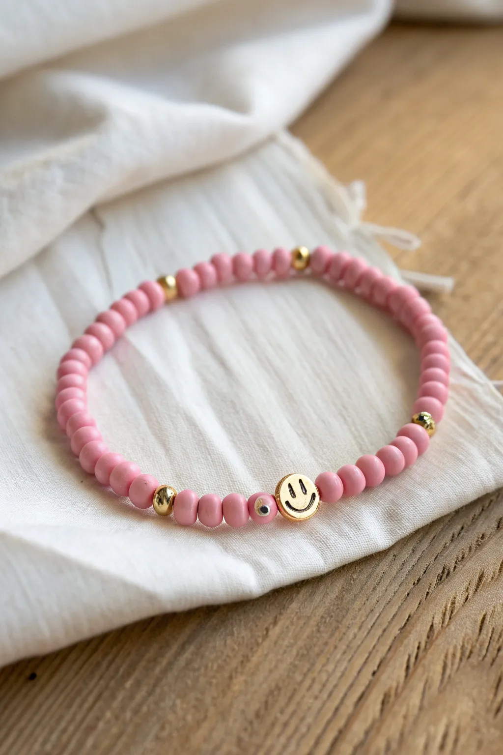 Bright pink clay bead bracelet with smiley accents and gold spacers for a playful pop look.