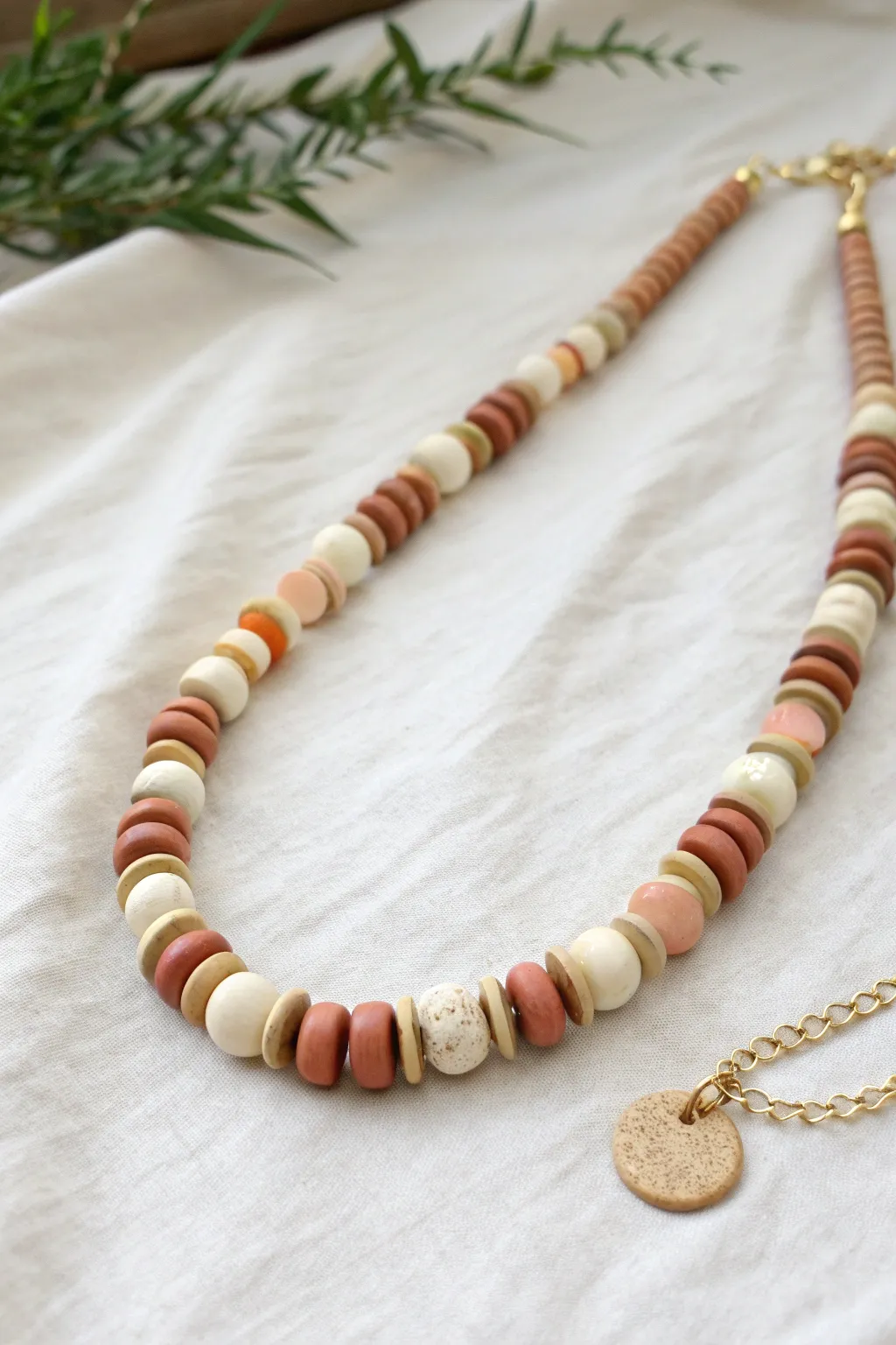 Minimal polymer clay disk and lentil bead necklace in soft neutrals, styled in a bright flat lay