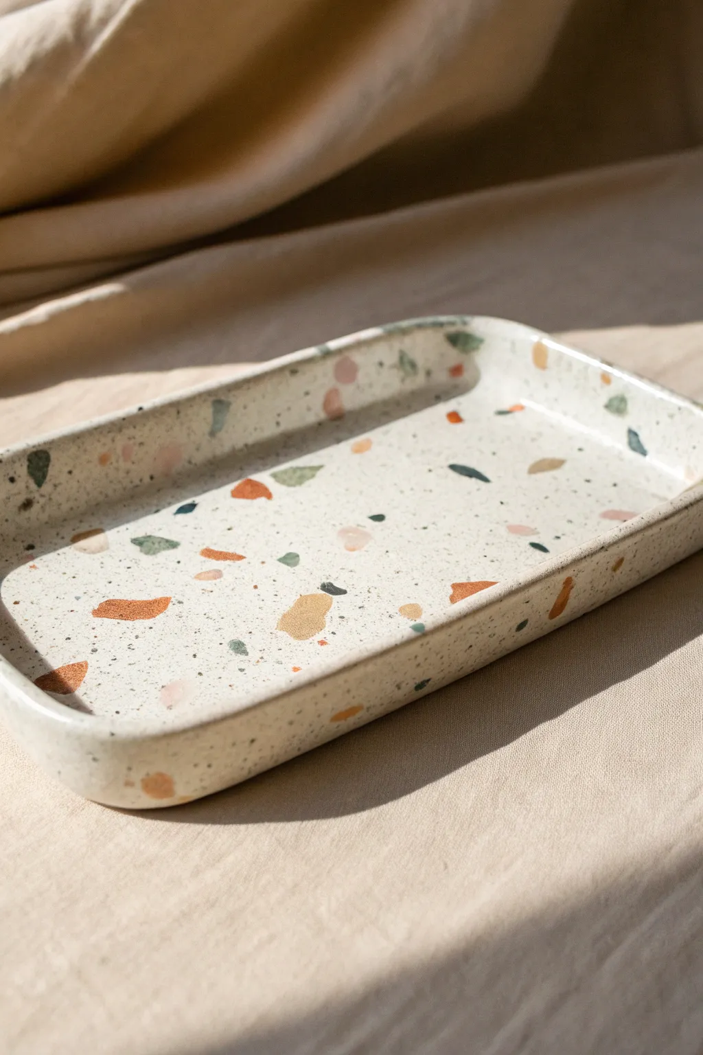 Terrazzo-speckled pottery tray in a soft matte glaze, minimalist and warm with crisp contrast.