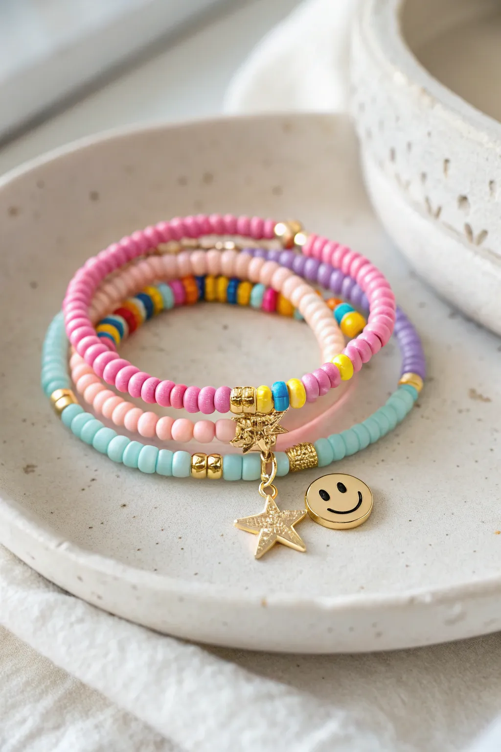 Preppy heishi bracelet stack with smiley bead and tiny star charm, finished with gold spacers.