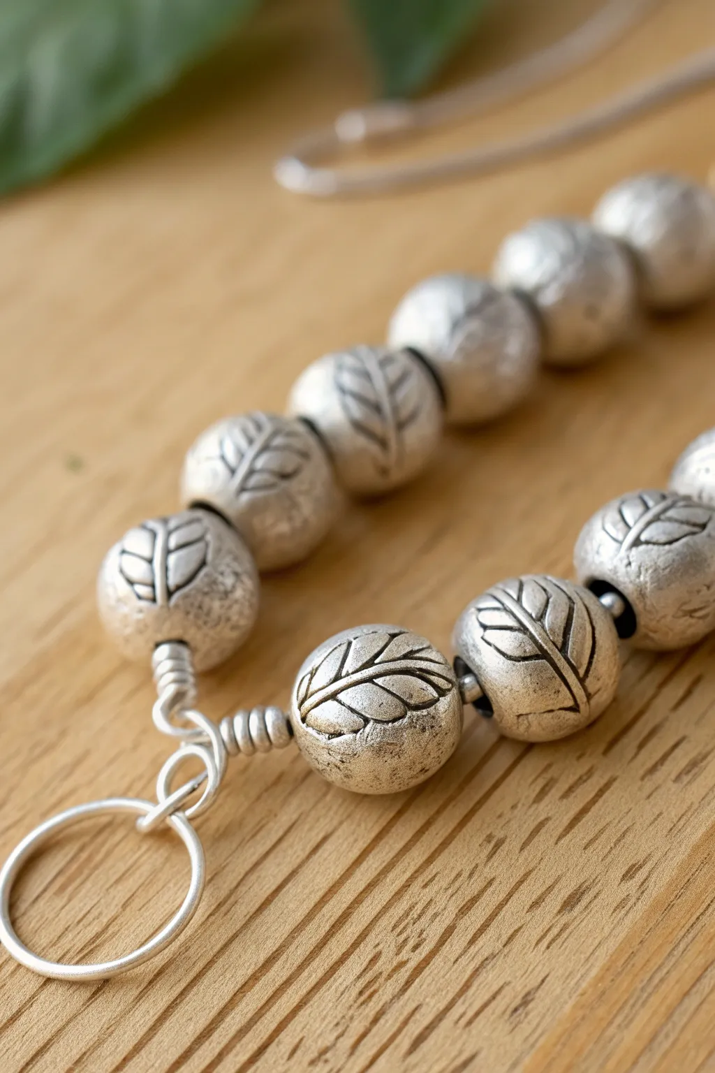 Tiny botanical silver clay beads with subtle leaf texture, styled simply on warm wood.