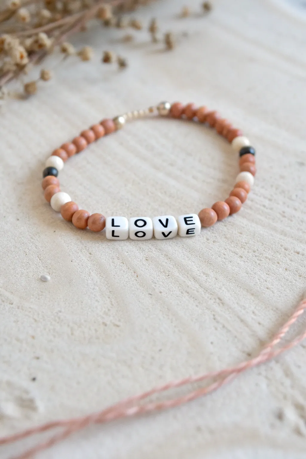 Simple LOVE letter bead bracelet with handmade clay beads in a clean Scandinavian flat lay