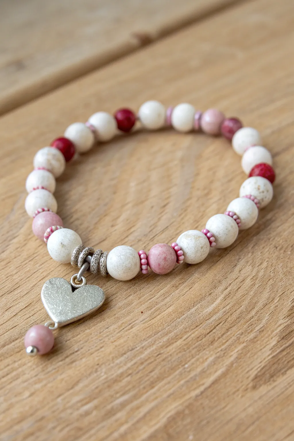 Sweet minimalist clay bracelet with a dangling heart charm and pink-red pops for Valentines.