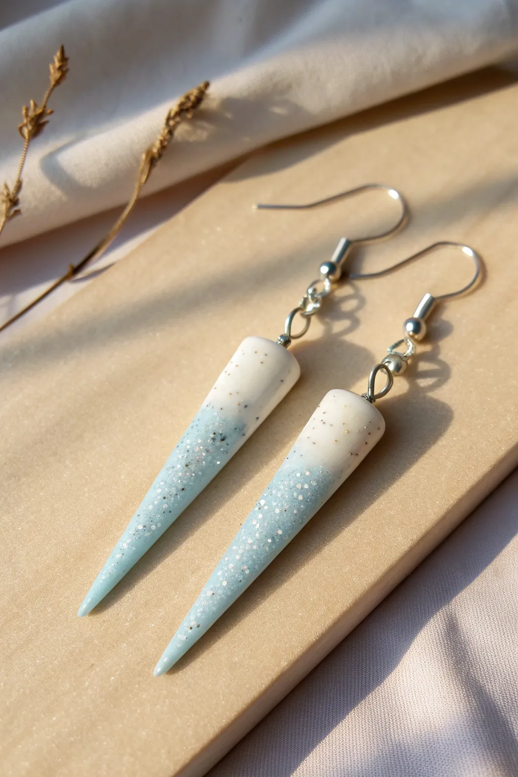 Minimalist icy clay icicle earrings in soft winter tones, crisp contrast and cozy linen backdrop